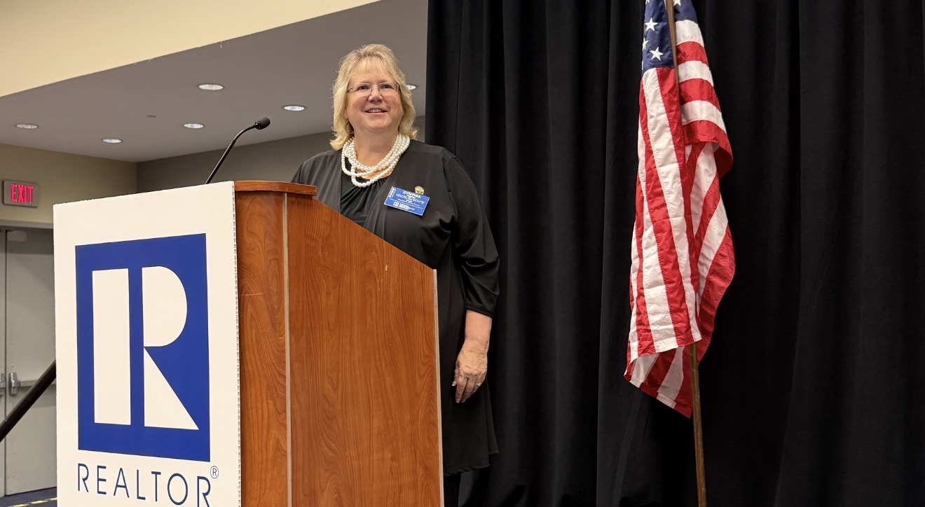 Cyndee Haydon 2026 NAR Regulatory Issues Forum Chair and Broker Associate Future Home Realty at Realtor-branded podium with American flag REALTORS Legislative Meetings Washington DC June 15 2026